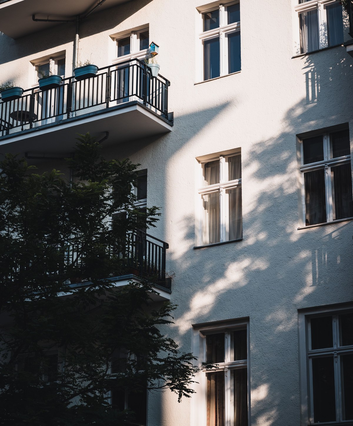 Helle Berliner Wohnhausfassade mit Balkonen und Fenstern im Sonnenlicht
